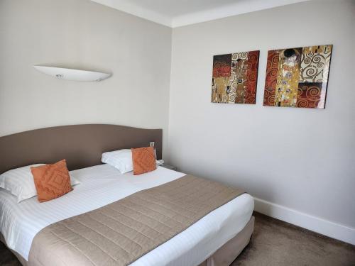 a bed in a room with two pictures on the wall at Hôtel Les Nations The Originals Boutique VICHY in Vichy