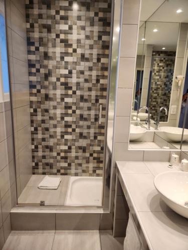 a bathroom with a tub and a sink and a mirror at Hôtel Les Nations The Originals Boutique VICHY in Vichy