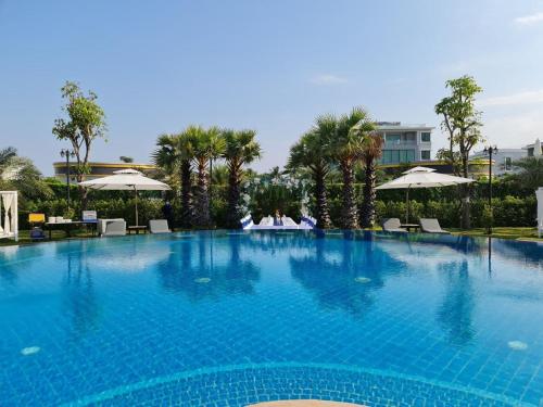 a large blue swimming pool with chairs and umbrellas at Castle Bayview Resort & Spa in Kampot
