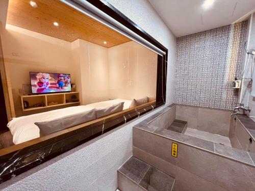 a bathroom with a tub and a bed and a television at 日月潭沅居民宿 YUAN JU BOUTIQUE Hotel in Yuchi