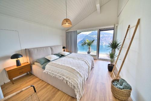 1 dormitorio con cama y ventana grande en Dreamview Retreat - Breathtaking Lake Views en Krattigen