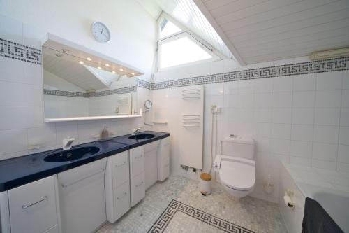 bagno bianco con lavandino e servizi igienici di Dreamview Retreat - Breathtaking Lake Views a Krattigen