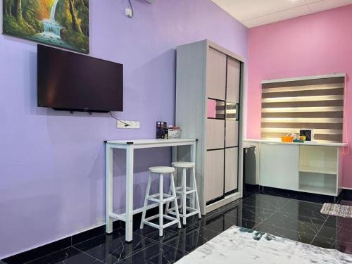 a room with a purple wall with stools and a tv at As Sufi Villa in Kampung Sungai Air Tawar