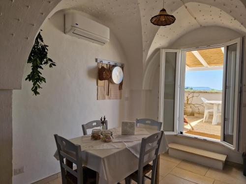 een eetkamer met een tafel en een groot raam bij Residenza "I Tre Carrubi " in Fasano