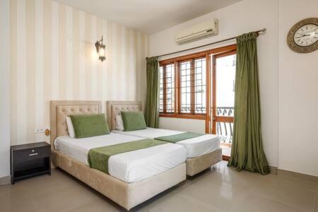um quarto com 2 camas e uma janela com um relógio em Elegant Apartment by JadeCaps Wifi Private balcony em Bangalore