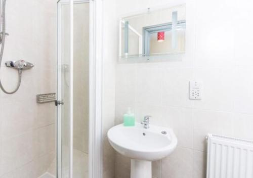 a white bathroom with a sink and a shower at Just Stay in Warsaw