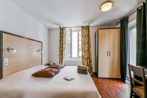 a bedroom with a large bed with a wooden headboard at Logis Hôtel le Commerce in Navarrenx
