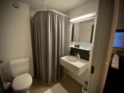 uma casa de banho com um WC, um lavatório e um espelho. em Struer Grand Hotel em Struer