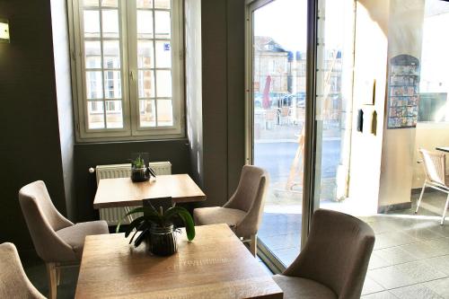 un restaurante con 2 mesas y sillas y una ventana en Logis Hôtel le Commerce, en Navarrenx