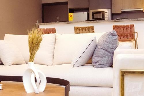 a white couch with pillows and a vase on a table at Luna Loft in Tema