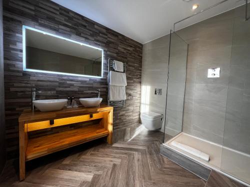uma casa de banho com 2 lavatórios, um chuveiro e uma banheira. em The Orchard Hotel & Restaurant em Nottingham