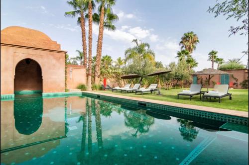 - une piscine avec des chaises et des palmiers à côté d'une maison dans l'établissement Villa Magtafa, à Marrakech