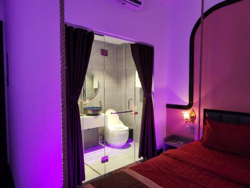 een paarse kamer met een badkamer met een bed bij Punita Hotel in Dien Ban