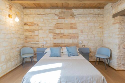 a bedroom with a bed and two blue chairs at Il Fiore del Conero in Sirolo