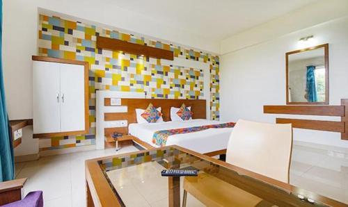 FabHotel Emirates Suites في بانغالور: غرفة نوم بسرير وطاولة زجاجية