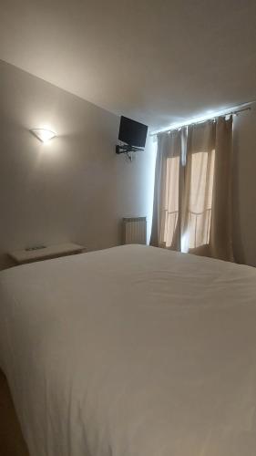 a bedroom with a large white bed and a television at Hostal Rural Sositana in Castejón de Sos