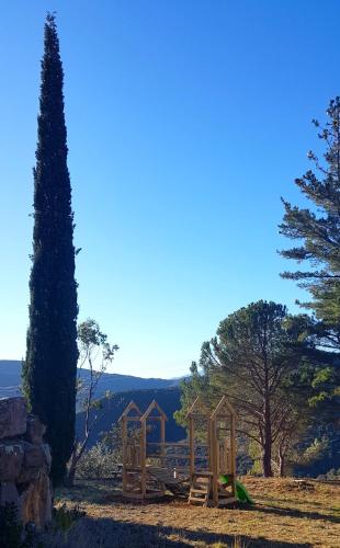 a group of wooden structures in a field with trees at Gites-Terroirs-Occitanie in Felluns