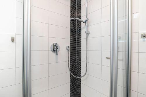 a shower in a bathroom with white tiles at Ferienwohnung Seeschwalbe in Schilksee