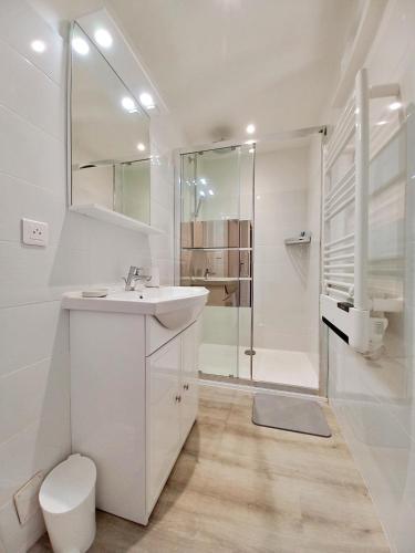 une salle de bain blanche avec un lavabo et une douche dans l'établissement Plage à 700m : Cocon Paisible, à Saint-Raphaël