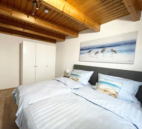 ein Schlafzimmer mit einem großen weißen Bett mit Vögeln an der Wand in der Unterkunft Nordseeferien Nessmersiel in Neßmersiel