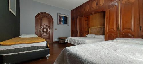a bedroom with two beds and a wooden cabinet at A Famosa CASA BRANCA Da Barra! Suíte 3 clássica! in Rio de Janeiro