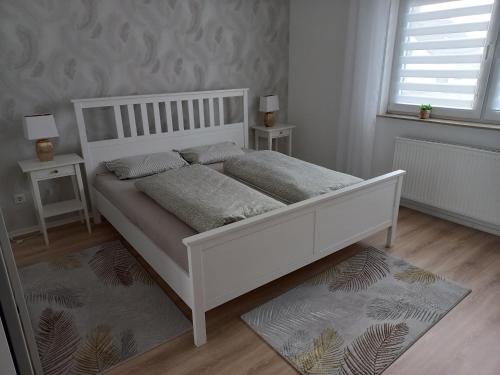 1 cama blanca en un dormitorio con 2 mesitas de noche en Ferienwohnung OLA, en Homburg