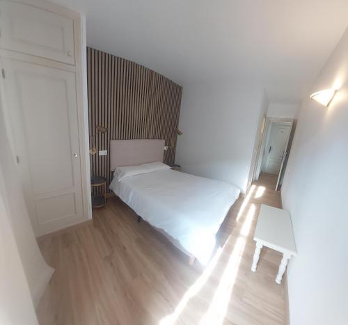 a bedroom with a white bed and a wooden floor at Hostal Rural Sositana in Castejón de Sos