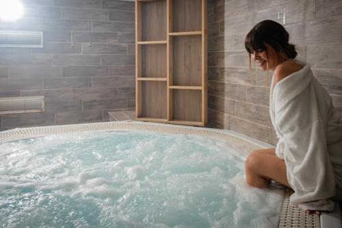 une femme assise dans un bain à remous dans une salle de bains dans l'établissement Hotel & Aparthotel Casteau Resort Mons Soignies, à Casteau