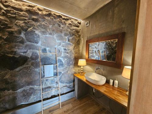 a bathroom with a sink and a stone wall at Les Terrasses Suites in Calheta