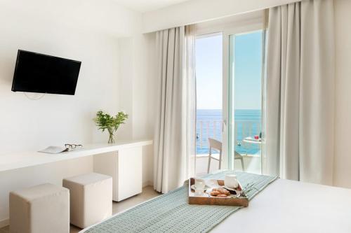 a white bedroom with a view of the ocean at Albatros Beach Hotel in Letojanni