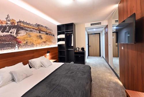 a bedroom with a large bed and a painting on the wall at Tvrdjava Rooms in Novi Sad