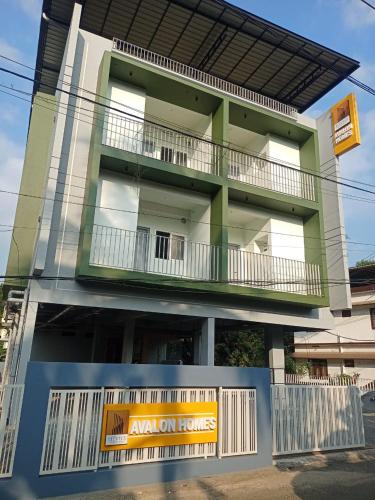a green building with a balcony on the side of it at Avalon Homes in Perintalmanna