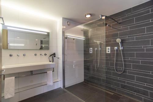 ein Bad mit einer Dusche, einem Waschbecken und einem Spiegel in der Unterkunft Najade Resort in Loosdrecht