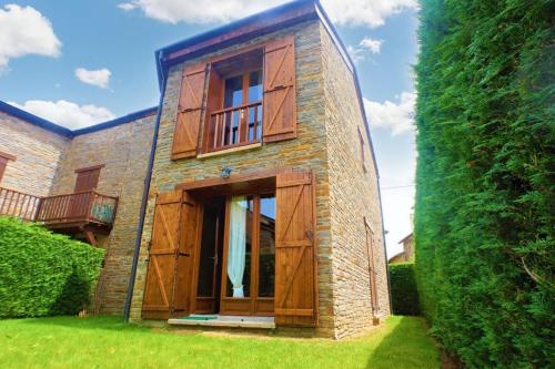 a brick house with wooden doors and a hedge at Casa Adosada con jardín y Wifi en Estavar in Estavar