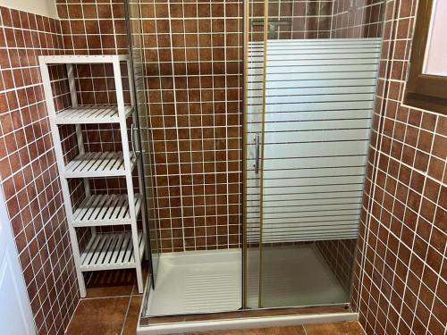 La salle de bains est pourvue d'une douche avec une porte en verre et des étagères. dans l'établissement Estavar III, à Estavar