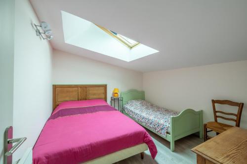a bedroom with a pink bed and a chair at Un Balcon sur le Port - Place de parking in Courseulles-sur-Mer