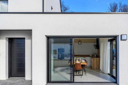 une maison blanche avec des portes en verre et une table dans l'établissement Le Ter - Maison avec grand jardin, 5mn de la plage, à Ploemeur
