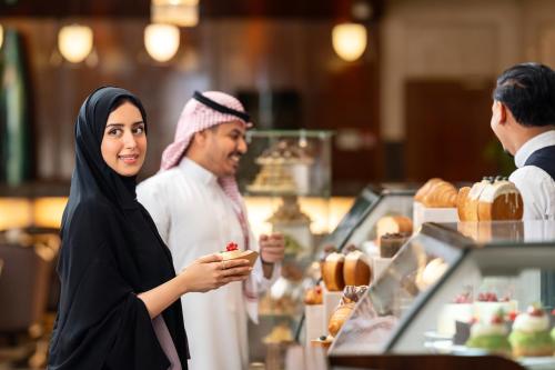 a woman standing in front of a bakery with a man at Swissotel Al Maqam Makkah in Makkah