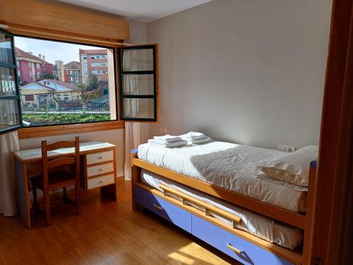 1 dormitorio con cama, escritorio y ventana en Casa con jardín y piscina en Muros, en Muros de Nalón