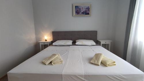 - un lit blanc avec 2 serviettes dans l'établissement Apartments Frankić, à Rab
