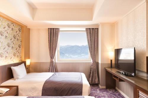 a hotel room with a bed and a window at Kokusai 21 International Hotel in Nagano