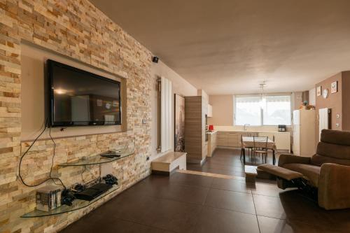 sala de estar con TV en una pared de ladrillo en Franciacorta Family Friendly, en Adro