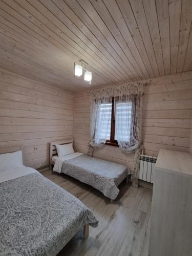 1 dormitorio con 2 camas en una cabaña de madera en КОТТЕДЖ У МОРЯ, en Chornomorsk