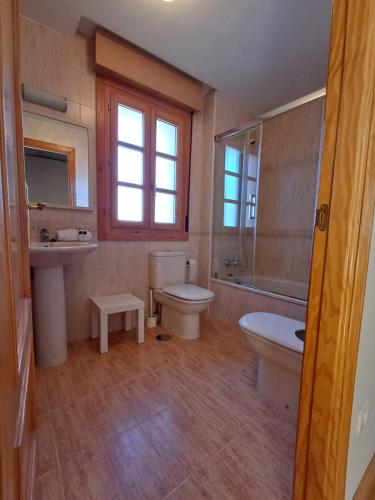 La salle de bains est pourvue de toilettes, d'un lavabo et d'une baignoire. dans l'établissement Casa con jardín y piscina en Muros, à Muros de Nalón