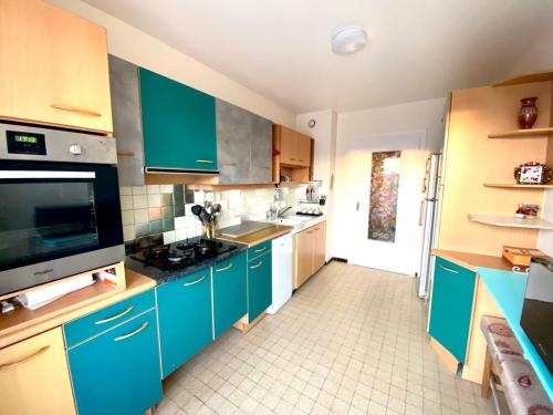 une grande cuisine avec des placards bleus et un évier dans l'établissement Appartement proche Gare, à Saint-Julien-en-Genevois