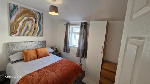 a bedroom with a bed with orange pillows and a window at Large Three Bedroom Apartment with Roof Terrace Near City Centre in Cardiff