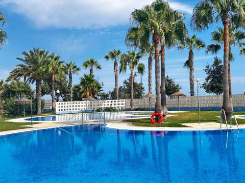 una gran piscina azul con palmeras en Luxurious Spacious Three Bedroom Apartment On Beachfront, en Almerimar