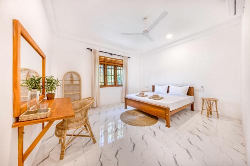 a white room with a desk and a bed at MAKAI Surf House in Ahangama