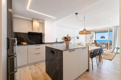 a kitchen with white cabinets and a black counter top at Alea Rentals - Bell Racó in La Pineda