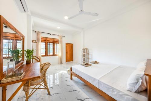 a bedroom with a bed and a desk and a table at MAKAI Surf House in Ahangama